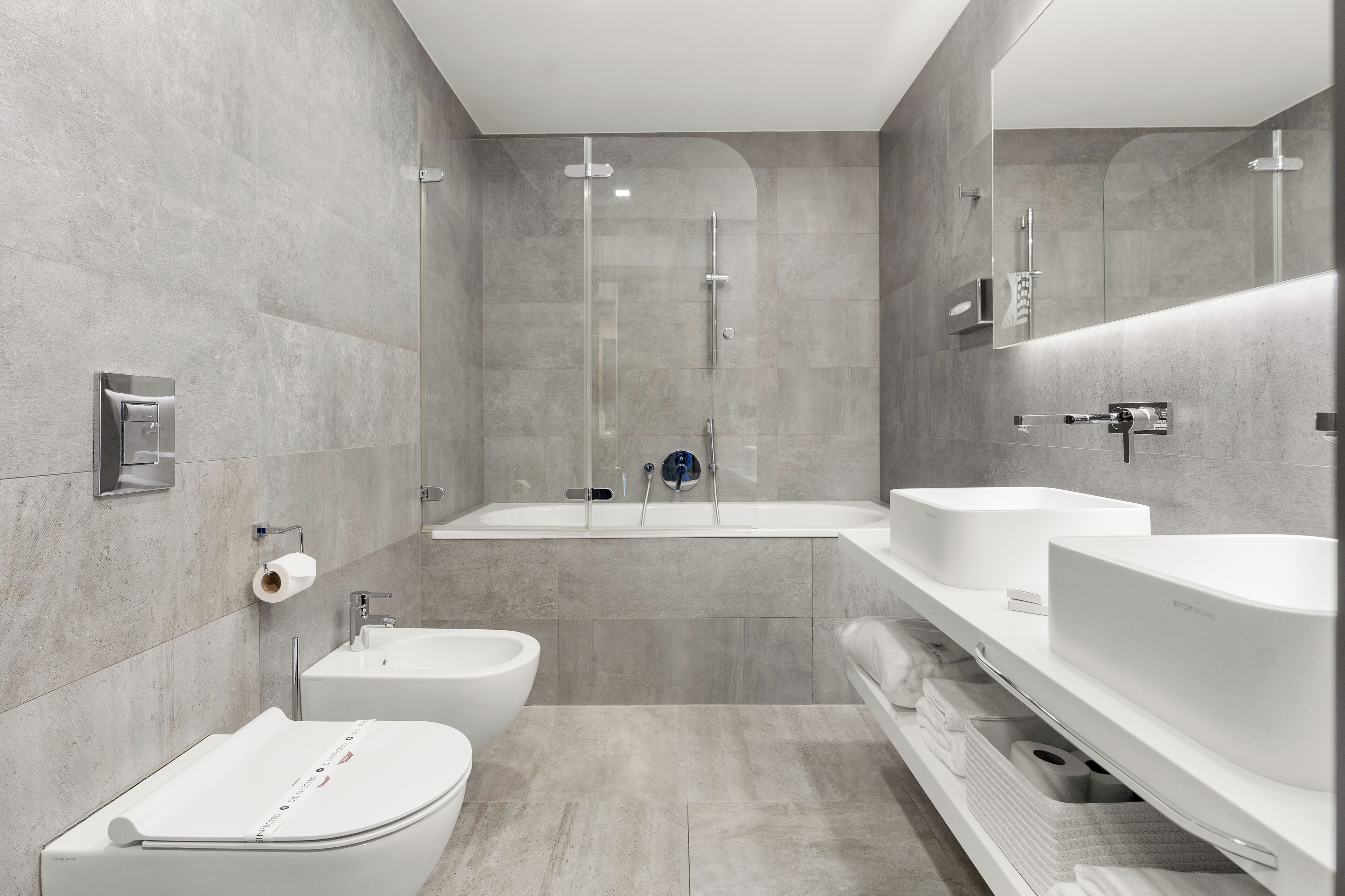 Une salle de bain moderne équipée d’un bidet, d’une baignoire et de deux lavabos.