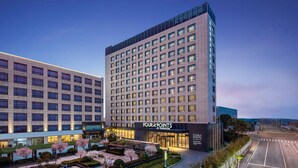 Un hotel moderno con un edificio grande y rectangular, que presenta una cuadrícula de ventanas y un llamativo letrero de "Four Points by Sheraton".