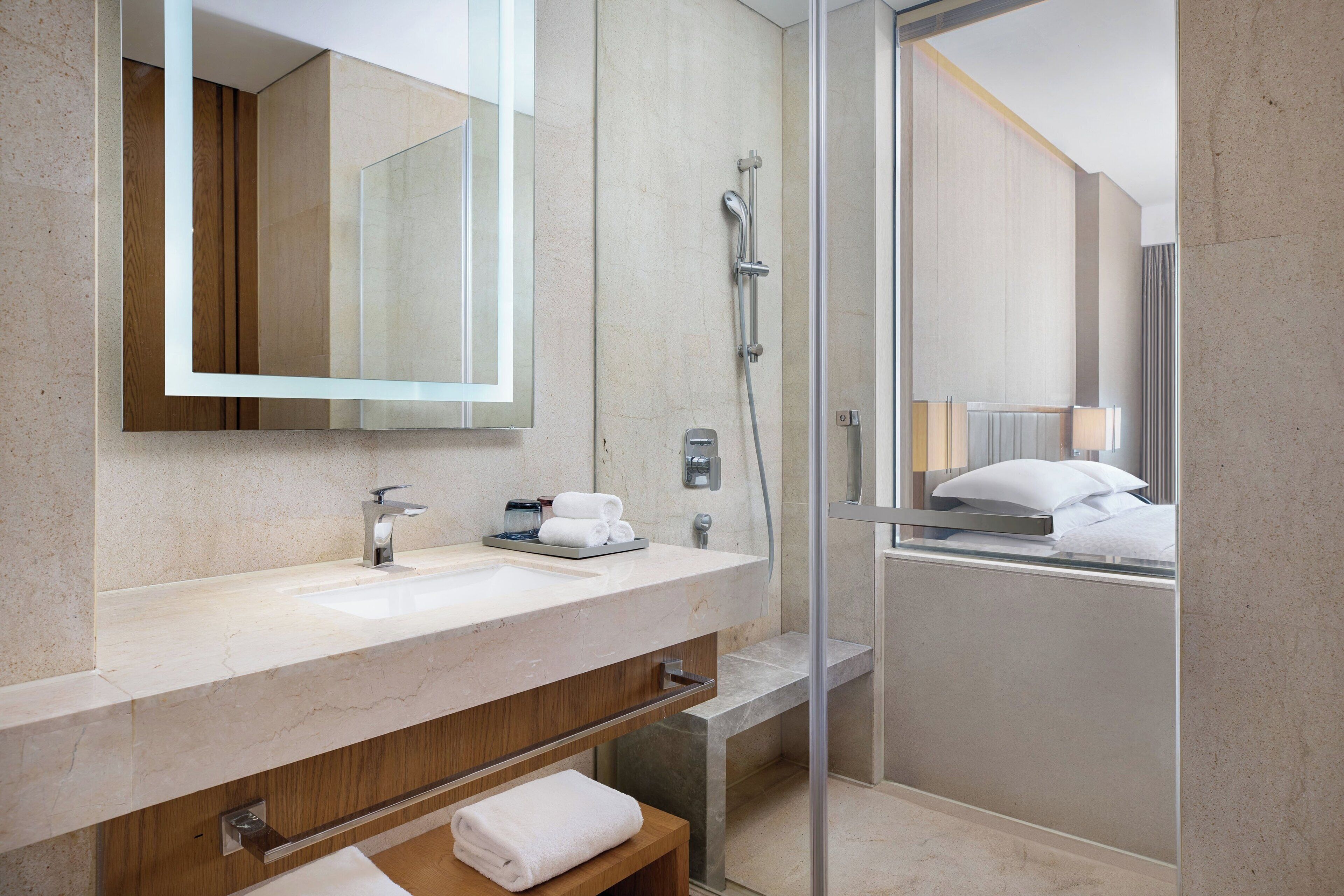 A modern bathroom with a marble sink, a glass shower enclosure, and a wooden vanity.