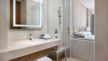 A modern bathroom with a marble sink, a glass shower enclosure, and a wooden vanity.