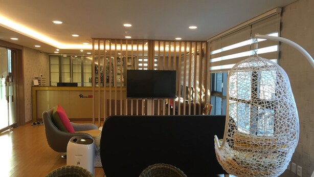 Una sala de estar moderna con un televisor de pantalla plana, un sofá, una mesa de centro y una lámpara colgante original.