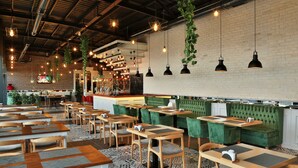 Un restaurante con varias mesas y sillas, luces colgantes y una pared de ladrillo.