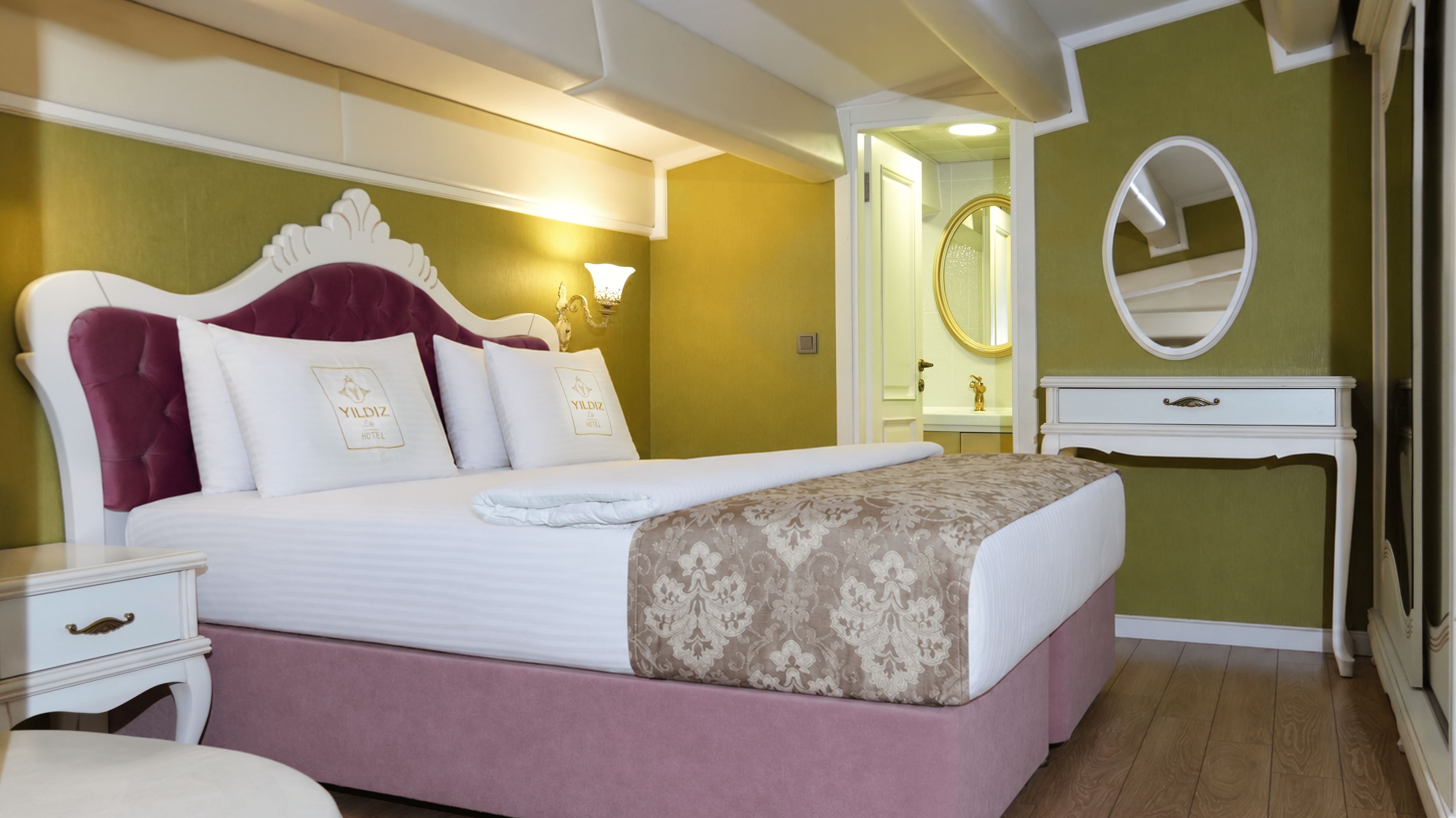 A hotel room with a bed, bedside table, and a mirror.