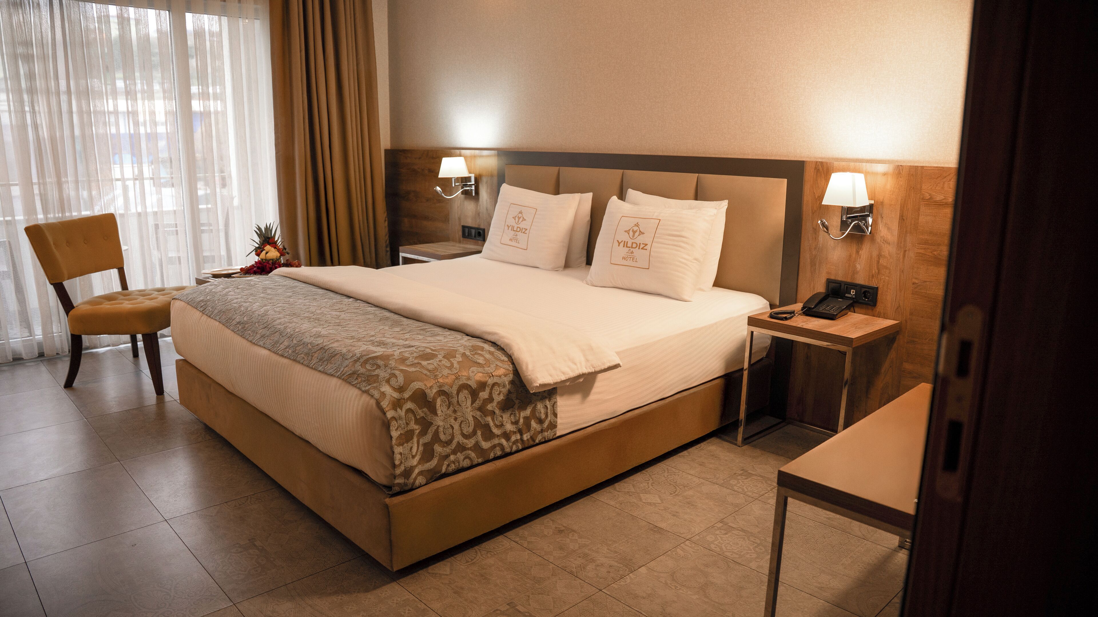 A hotel room with a large bed, two bedside tables with lamps, a chair, and a small table.