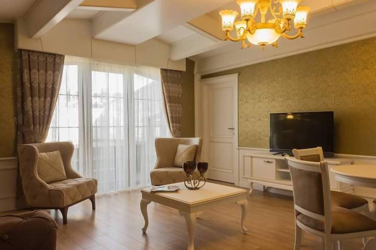 A living room with a chandelier, a television, and a dining area.