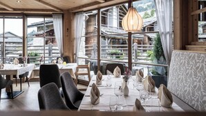 Un restaurant à l’intérieur en bois, doté de grandes fenêtres et offrant une vue sur des bâtiments traditionnels.