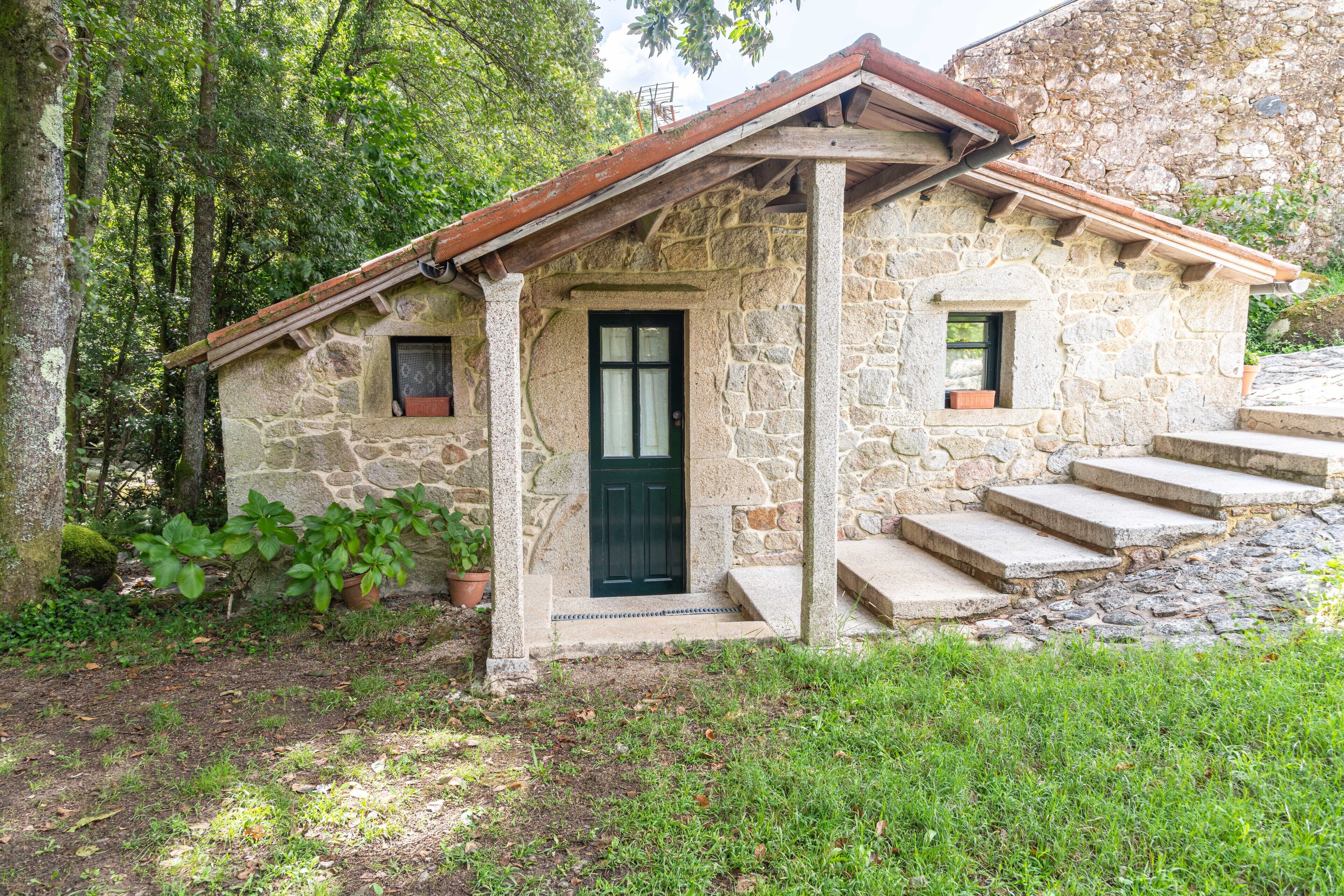 A stone house with a tiled roof, a front door, and a small window.