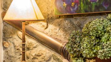 A stone wall with a painting of flowers, a lamp, a small bowl, and a potted plant.