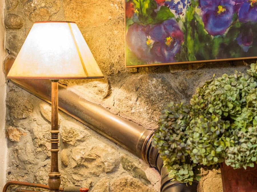 A stone wall with a painting of flowers, a lamp, a small bowl, and a potted plant.