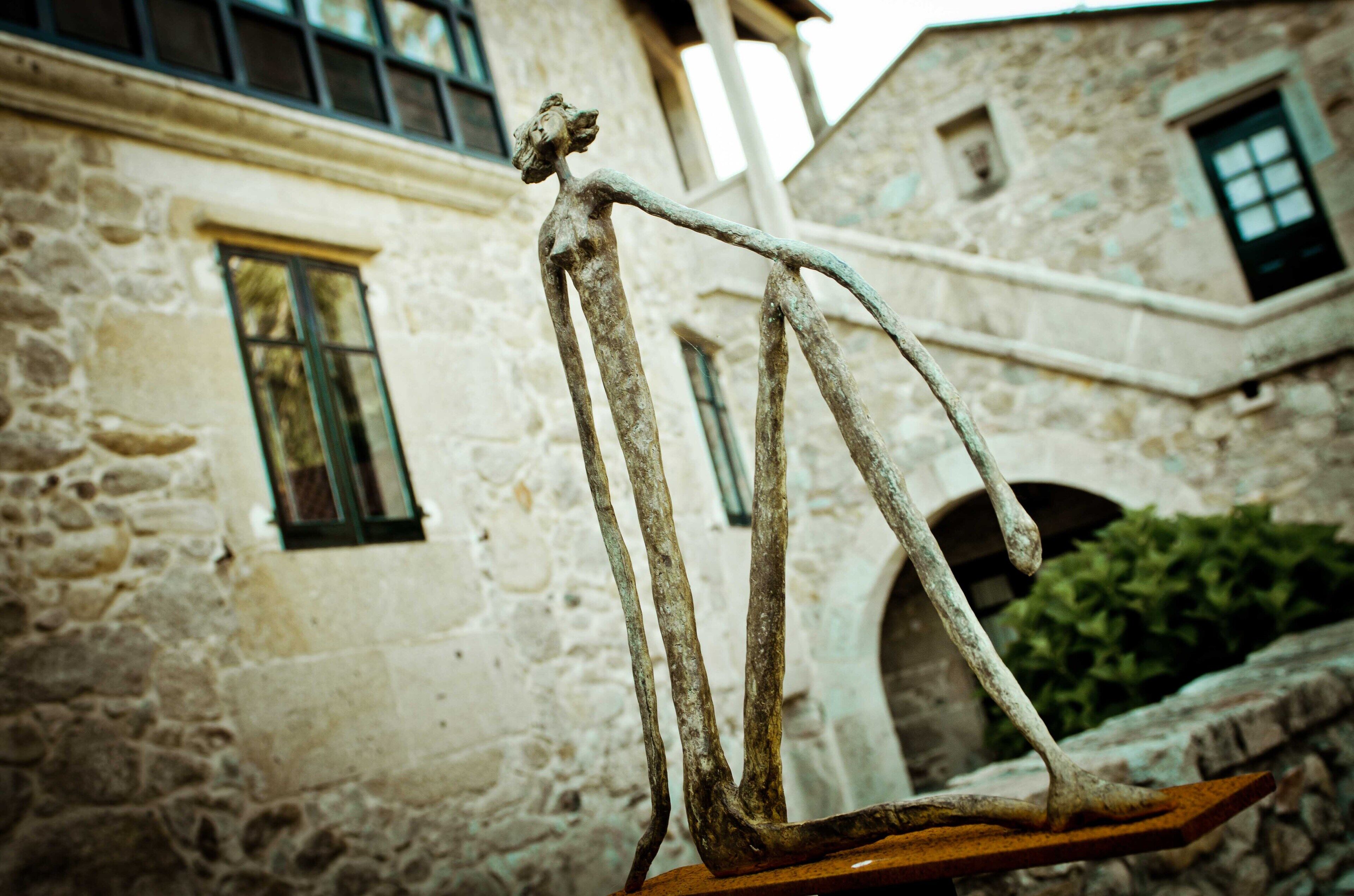Un edificio rústico de piedra con una estatua de una figura sobre una plataforma de madera.