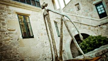 Un edificio rústico de piedra con una estatua de una figura sobre una plataforma de madera.