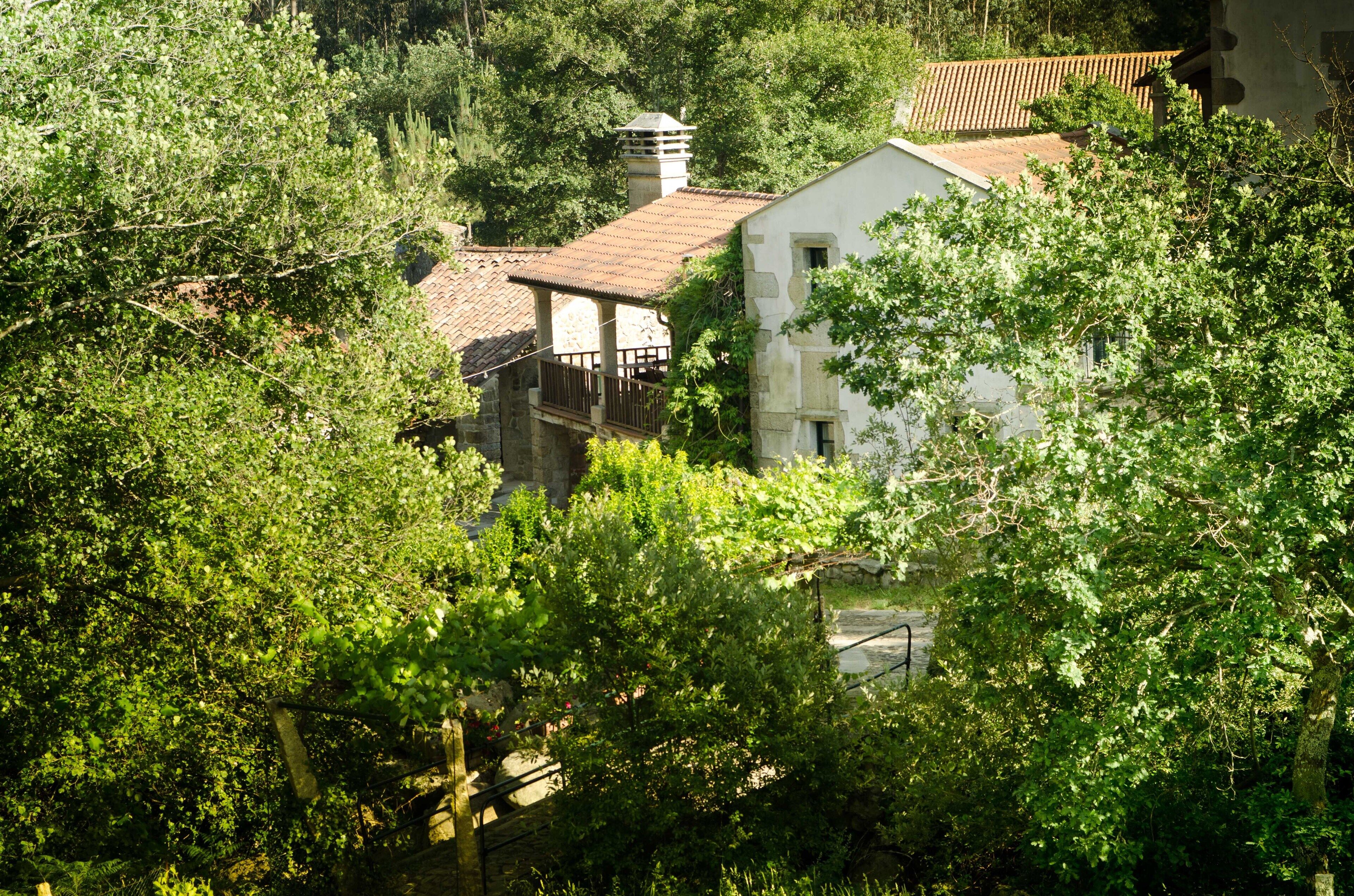 A rustic building with a tiled roof, surrounded by dense greenery.