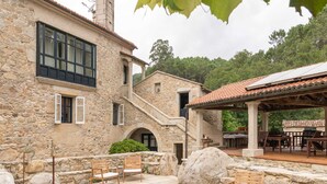 Edifici de pedra amb pati que té mobles d'exterior i plantes en testos.