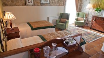 Una habitación acogedora con una cama, dos sillones, un aparador de madera y una mesa con varios objetos.