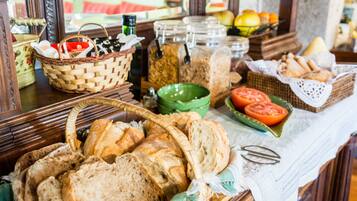 A buffet table with various breads, tomatoes, and jars of condiments.