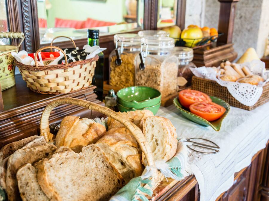A buffet table with various breads, tomatoes, and jars of condiments.
