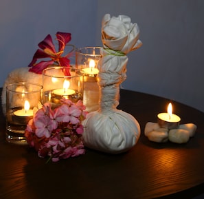 Una mesa con velas, un objeto envuelto en tela blanca y flores rosadas.
