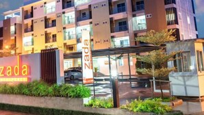 Ein mehrstöckiges Hotel mit modernem Design, mit Balkonen und einem überdachten Eingangsbereich.