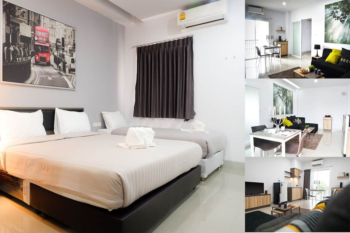 A hotel room with a large bed, a desk, a chair, a small table, and a window with curtains.