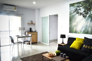 A modern living room with a black sofa, a coffee table, and a dining area with a table and chairs.