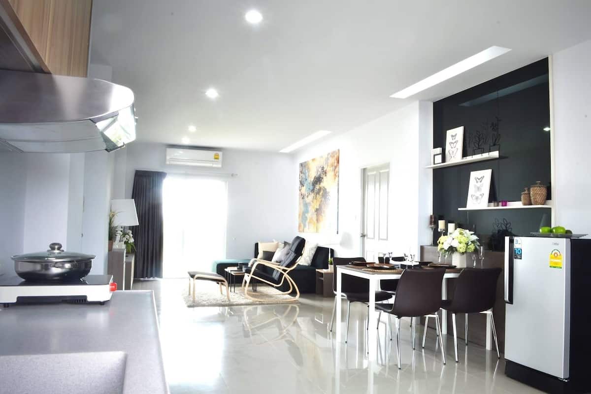 A modern kitchen with a dining area, a sofa, and a refrigerator.