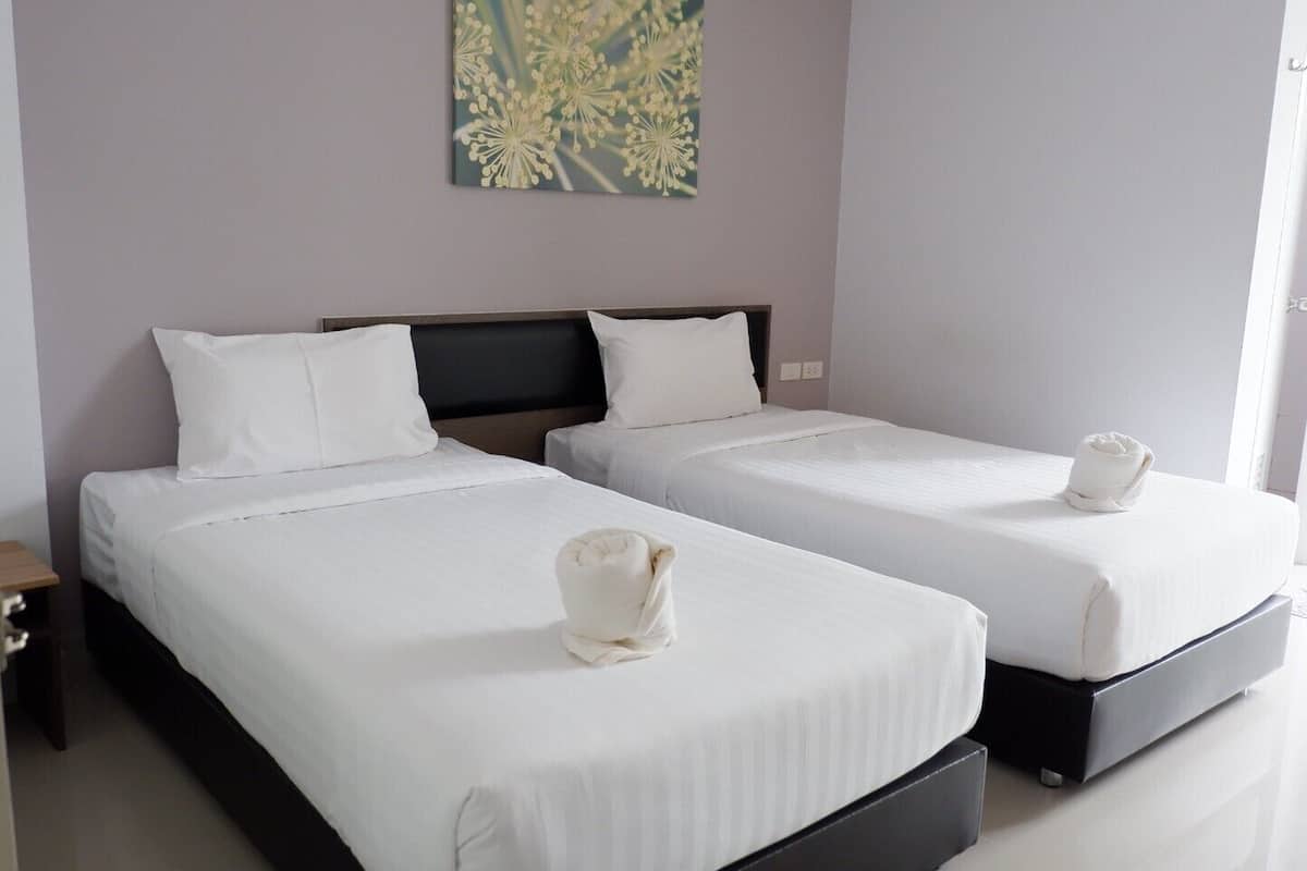 Two single beds with white linens and headboards, a small bedside table, and a wall-mounted artwork.