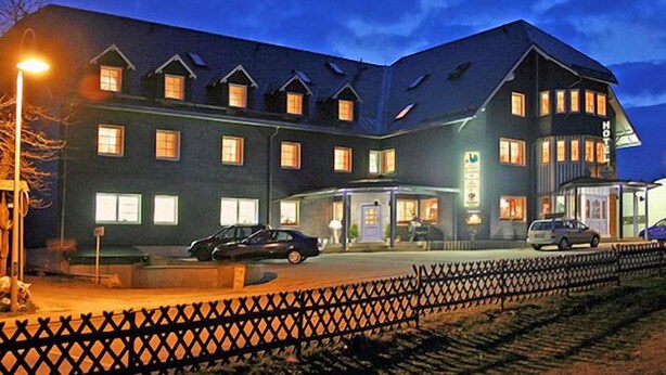 Un hotel grande de varios pisos con fachada oscura y numerosas ventanas.