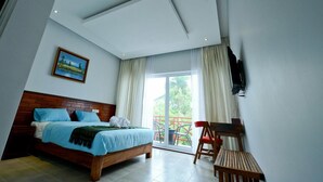 Un dormitorio con cama, televisor montado en la pared y balcón con sillas.