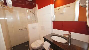 A modern bathroom with a glass-enclosed shower, a white toilet, and a granite countertop sink.