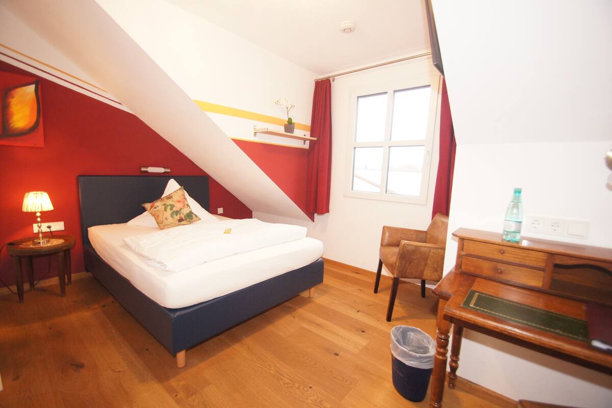 Un dormitorio con una cama, un escritorio, una silla, una lámpara y una ventana.