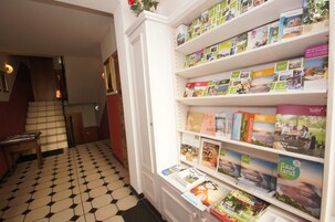 Un pasillo con piso de baldosas y una estantería llena de libros de viajes.