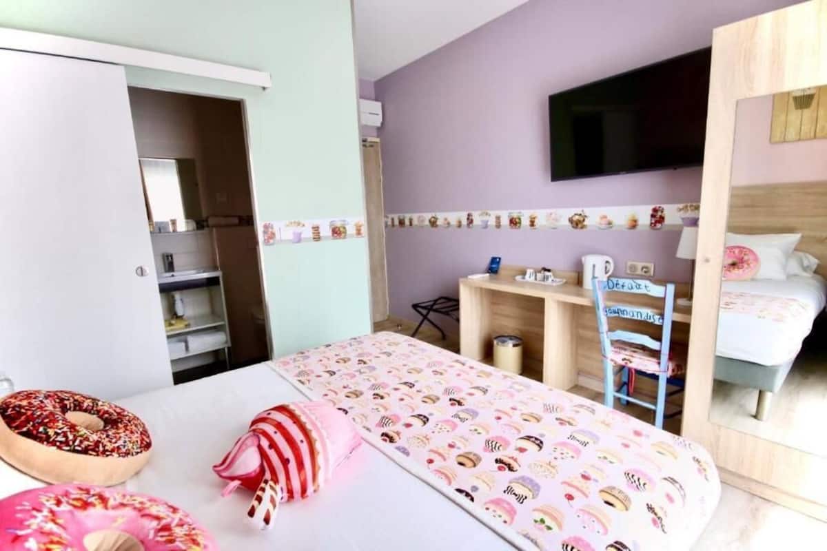 A bedroom with a bed, a desk, a chair, and a TV on the wall.