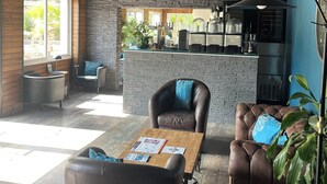 Un interior moderno con pared de piedra, asientos de cuero, una mesa de centro de madera y una zona de cocina con barra.