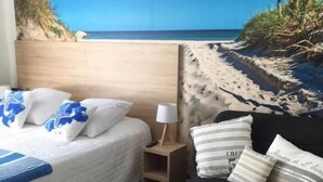 Un dormitorio con una cama, una mesita de noche, una lámpara y un sofá negro.