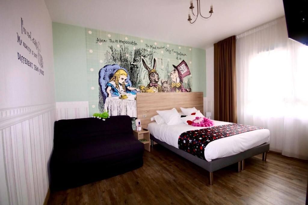 Un dormitorio con una cama, un sofá negro, un mural en la pared y una ventana con cortinas.