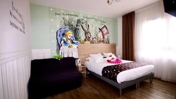 Un dormitorio con una cama, un sofá negro, un mural en la pared y una ventana con cortinas.