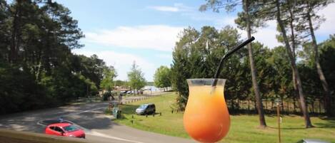 A drink on a table with a view of a road and trees.