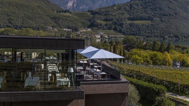 Un restaurante con terraza al aire libre, con vistas a un valle y montañas.