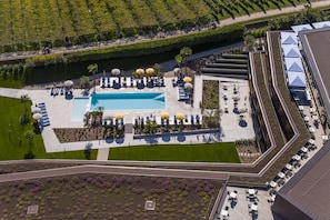 An aerial view of a hotel with a swimming pool, sun loungers, and a landscaped garden.