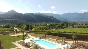 Un resort con piscina, tumbonas y vistas a viñedos.