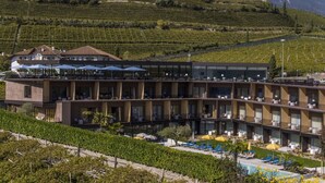 Un hotel con varios pisos, zona de estar exterior y piscina.
