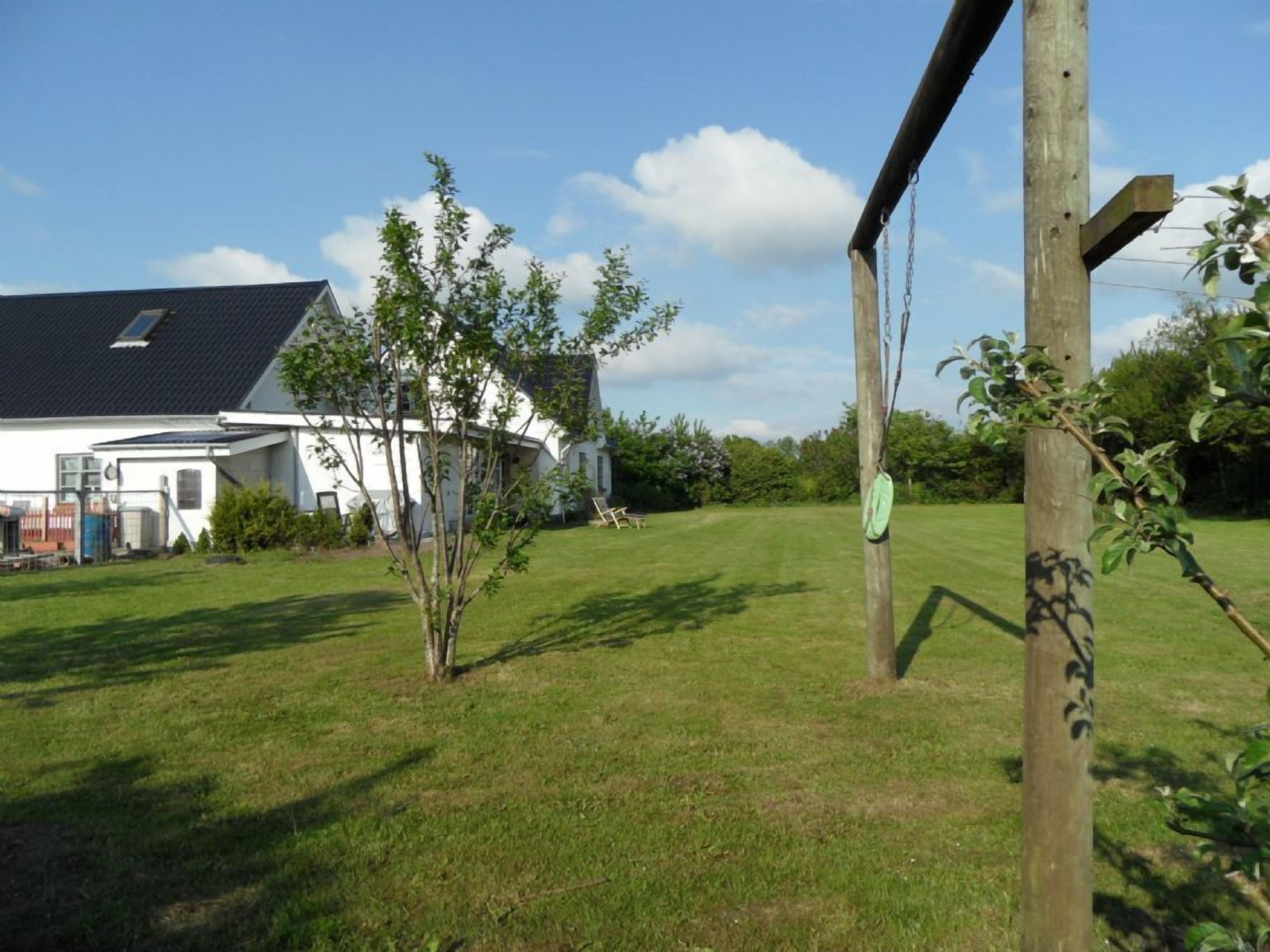 A grassy yard with a wooden swing set and a small tree.