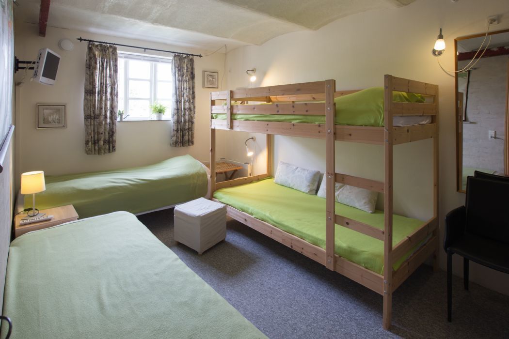 A room with bunk beds, a desk, a chair, a lamp, and a window with curtains.