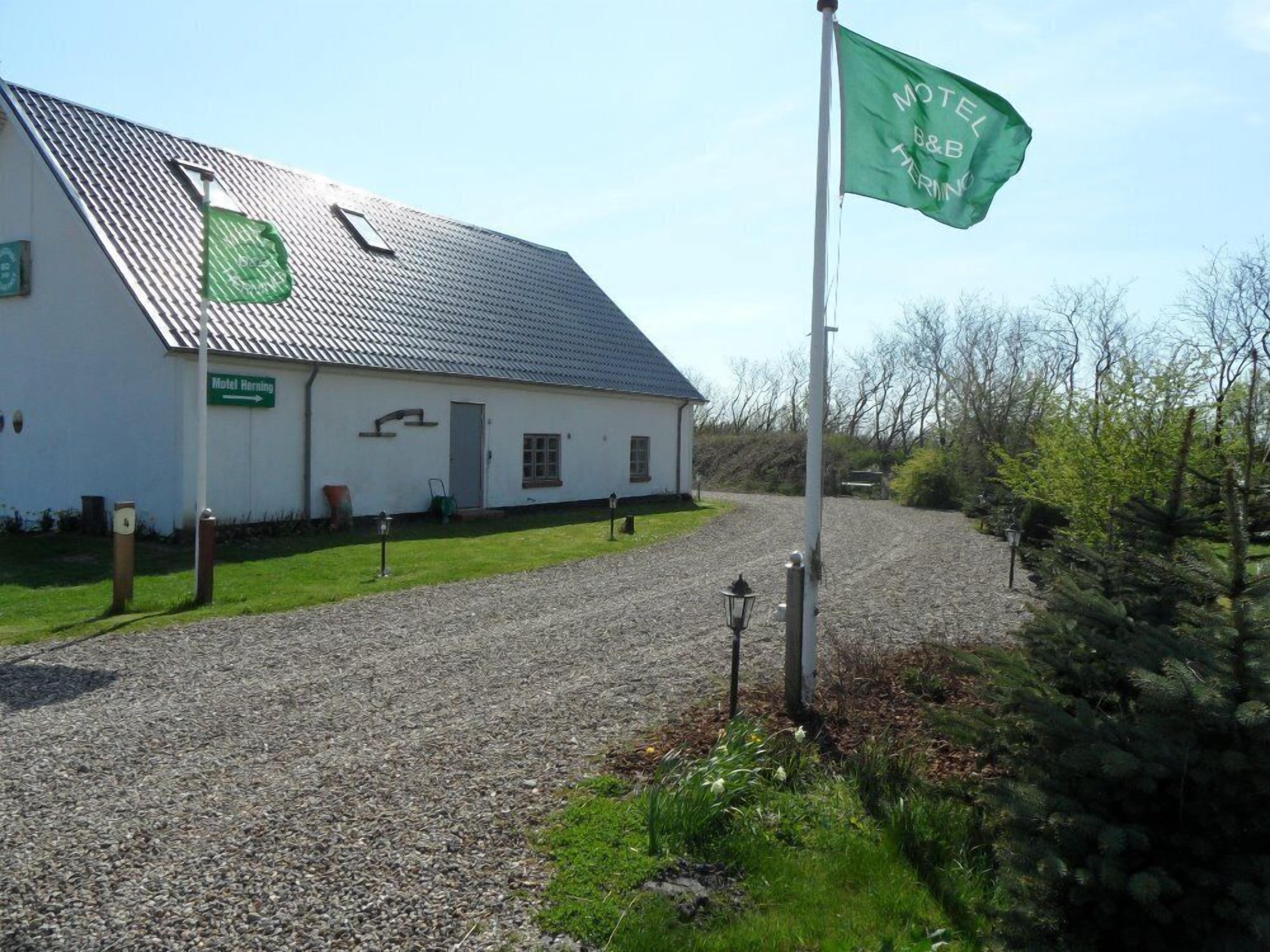 A white building with a gravel driveway and a flag.