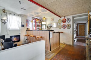 Una sala de estar acogedora con chimenea, una zona de bar de madera y un comedor con vistas a la calle.