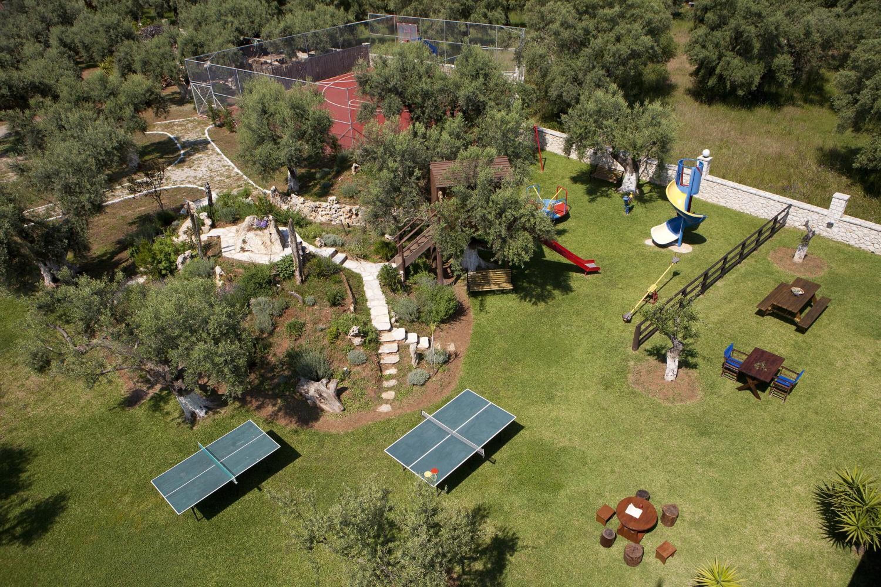 Ein Freizeitareal mit Basketballfeld, Spielplatz und Picknicktischen.