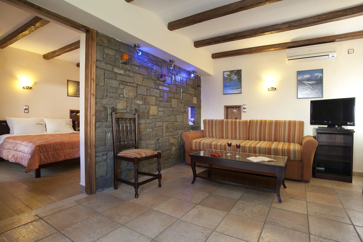 Una sala de estar acogedora con pared de piedra, un sofá, una mesa de centro y un televisor.