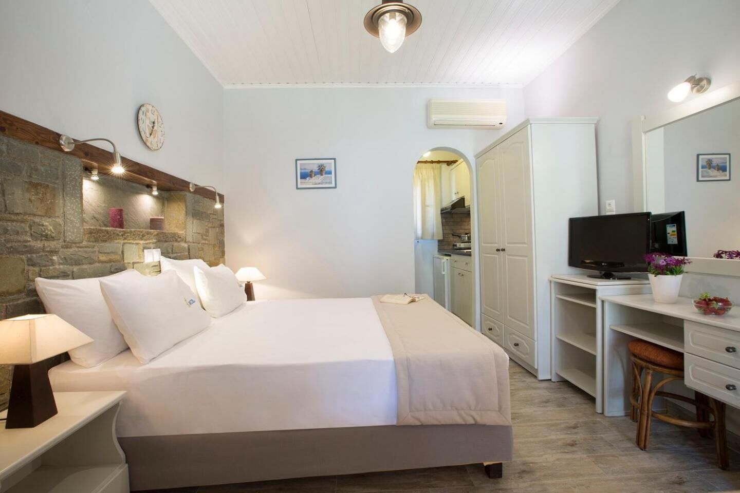A bedroom with a bed, bedside tables, a desk, a television, and a wardrobe.