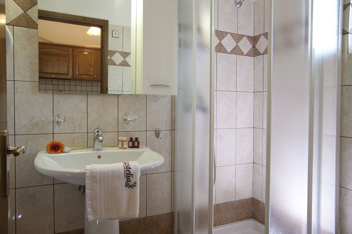 A bathroom with a sink, mirror, and shower.