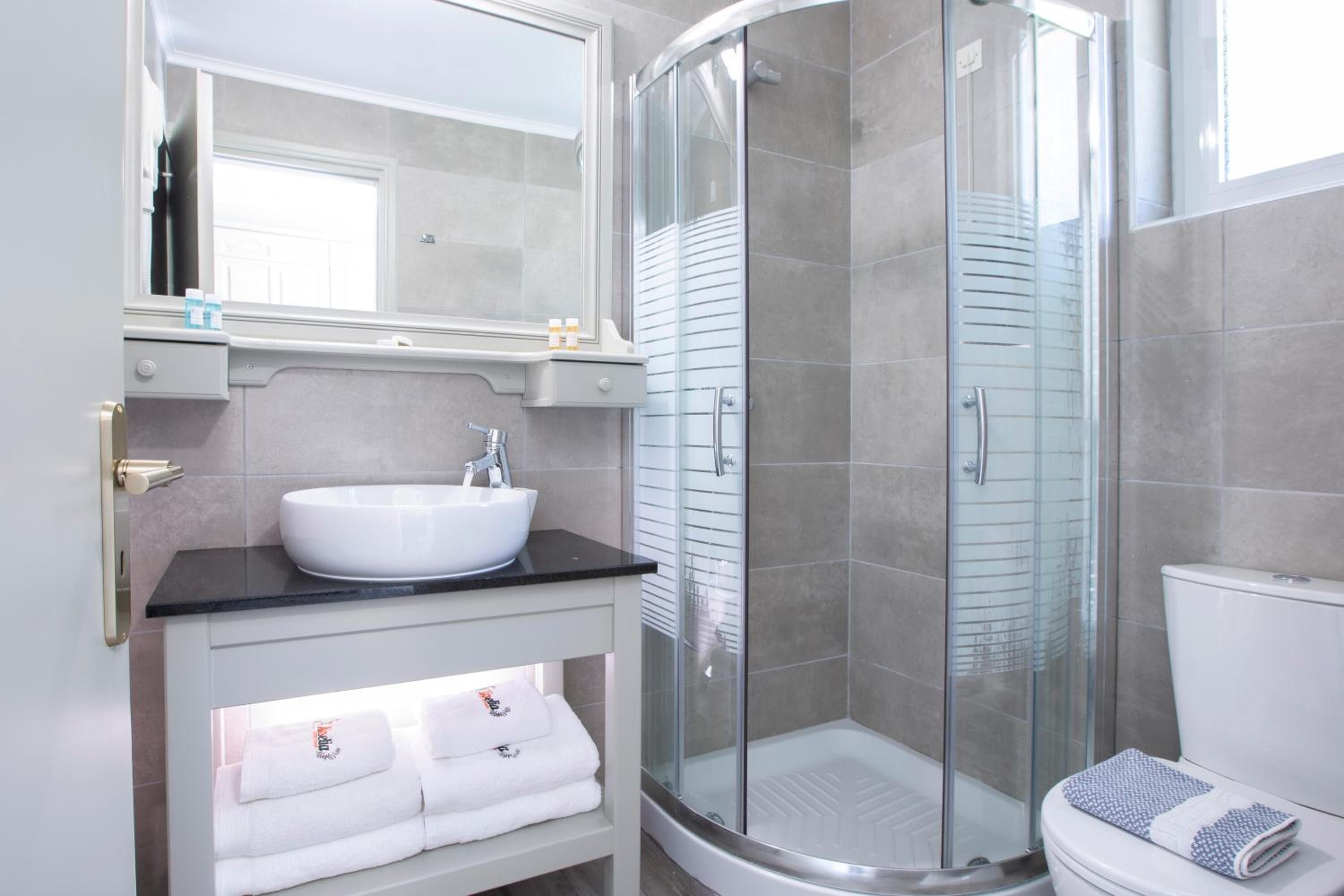 Un baño moderno con un lavamanos blanco, cabina de ducha con mampara de vidrio y un inodoro.